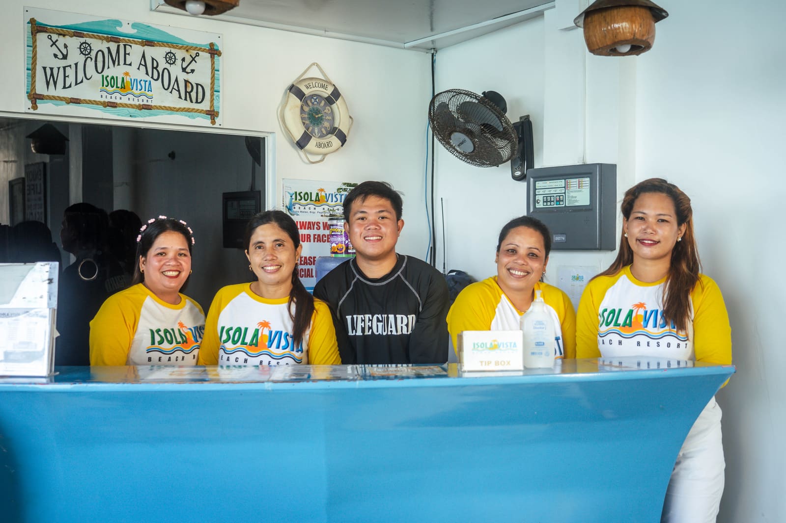 The Isola Vista Beach Resort front desk team and lifeguard at the Welcome Aboard counter