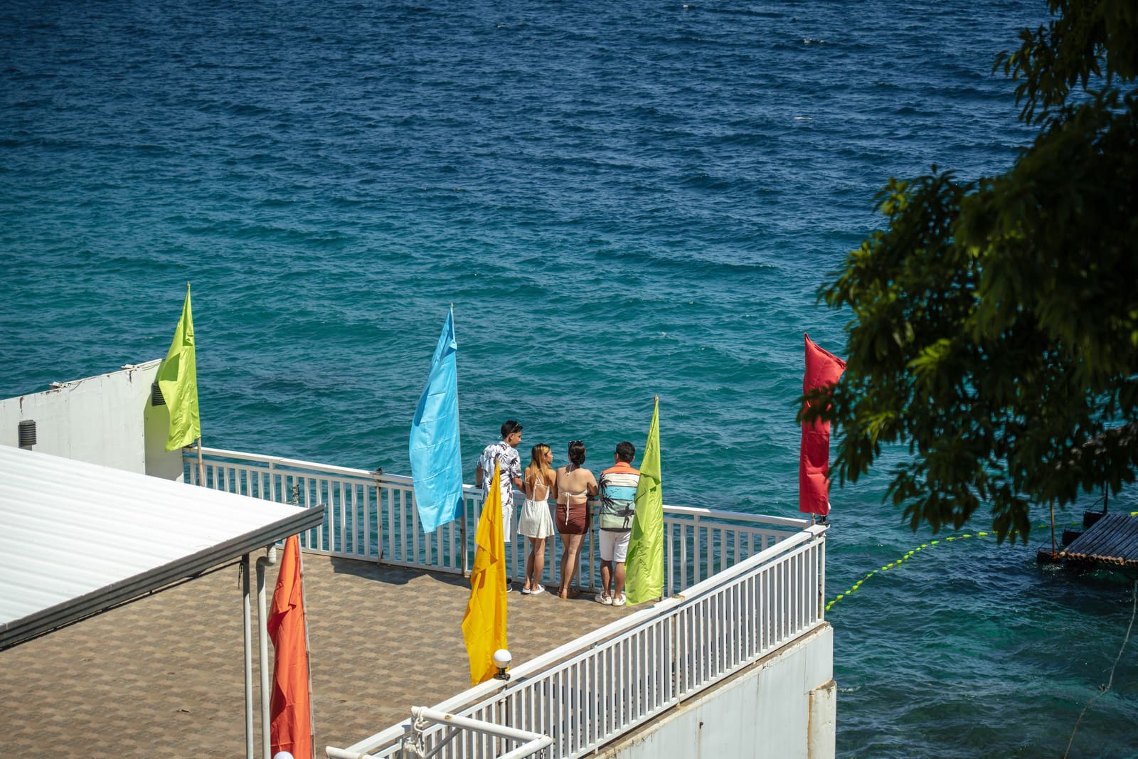Guests on the flag-lined viewing deck above Batangas Bay at Isola Vista Beach Resort